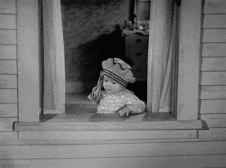 Movie gif. A toddler on Our Gang carelessly tosses a handful of money out an open window.
