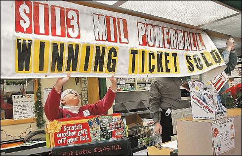 Store celebrates: Dahl's employee Dixie Upenieks helps put up a banner Thursday announcing that the winning Powerball ticket was sold at the Beaver Avenue store.
